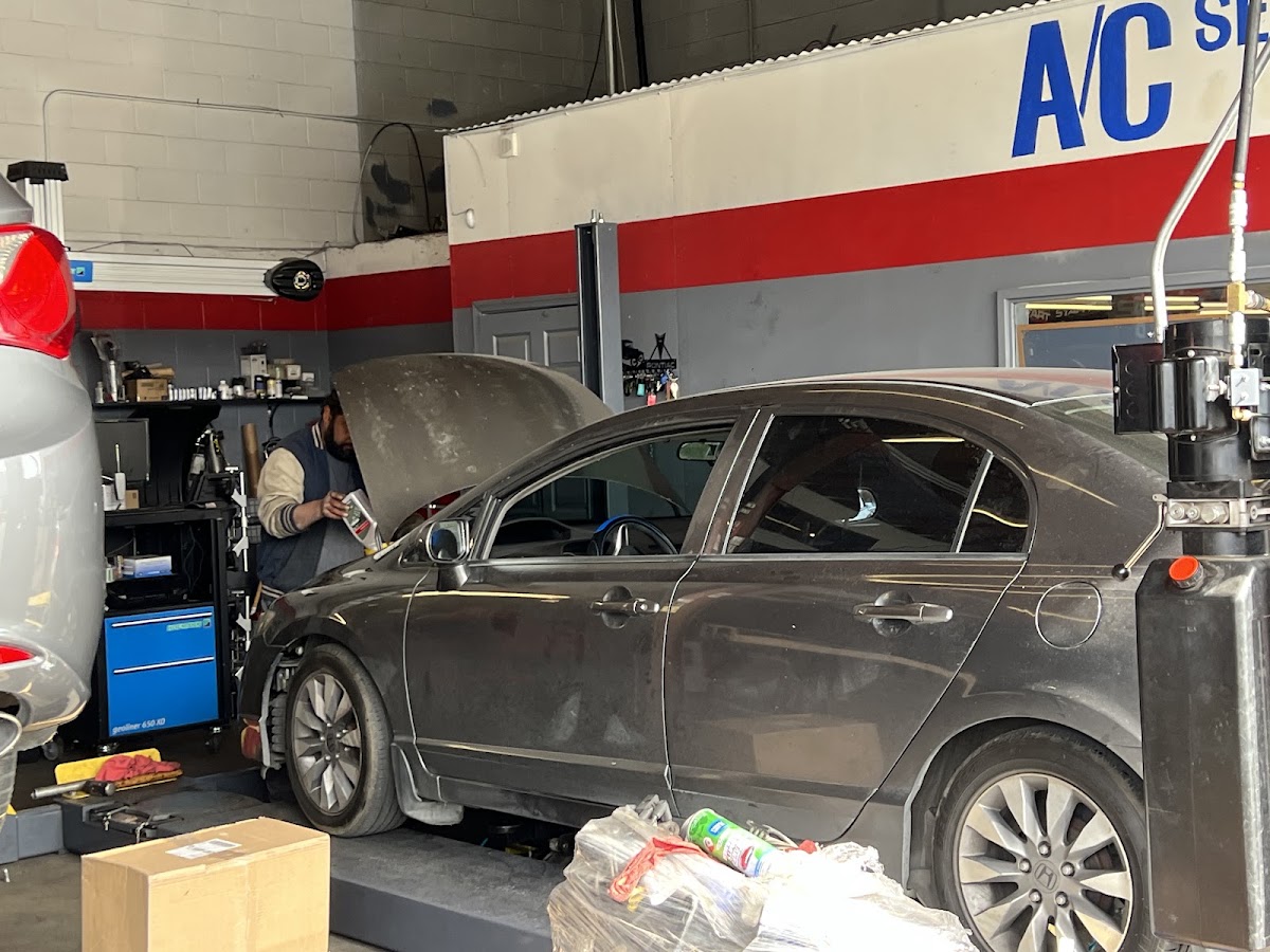 A car in the bay under the A/C Service sign at Intake Auto Repair